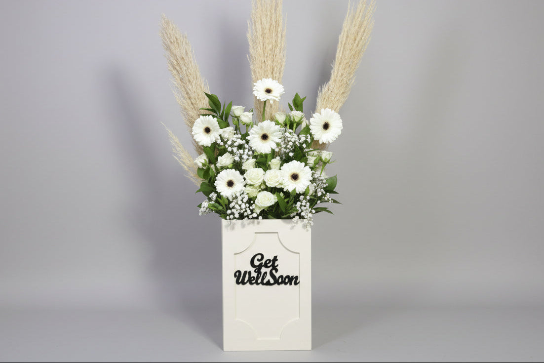 Floral arrangement in a 'Get Well Soon' box on a gray background